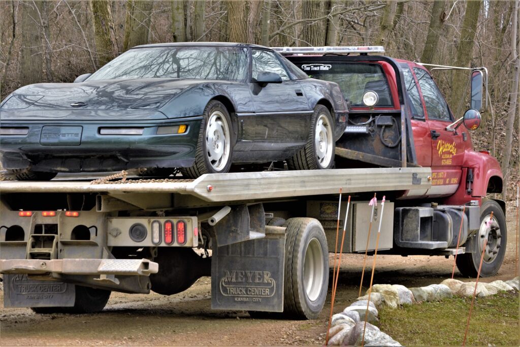 A truck carrying a black car  