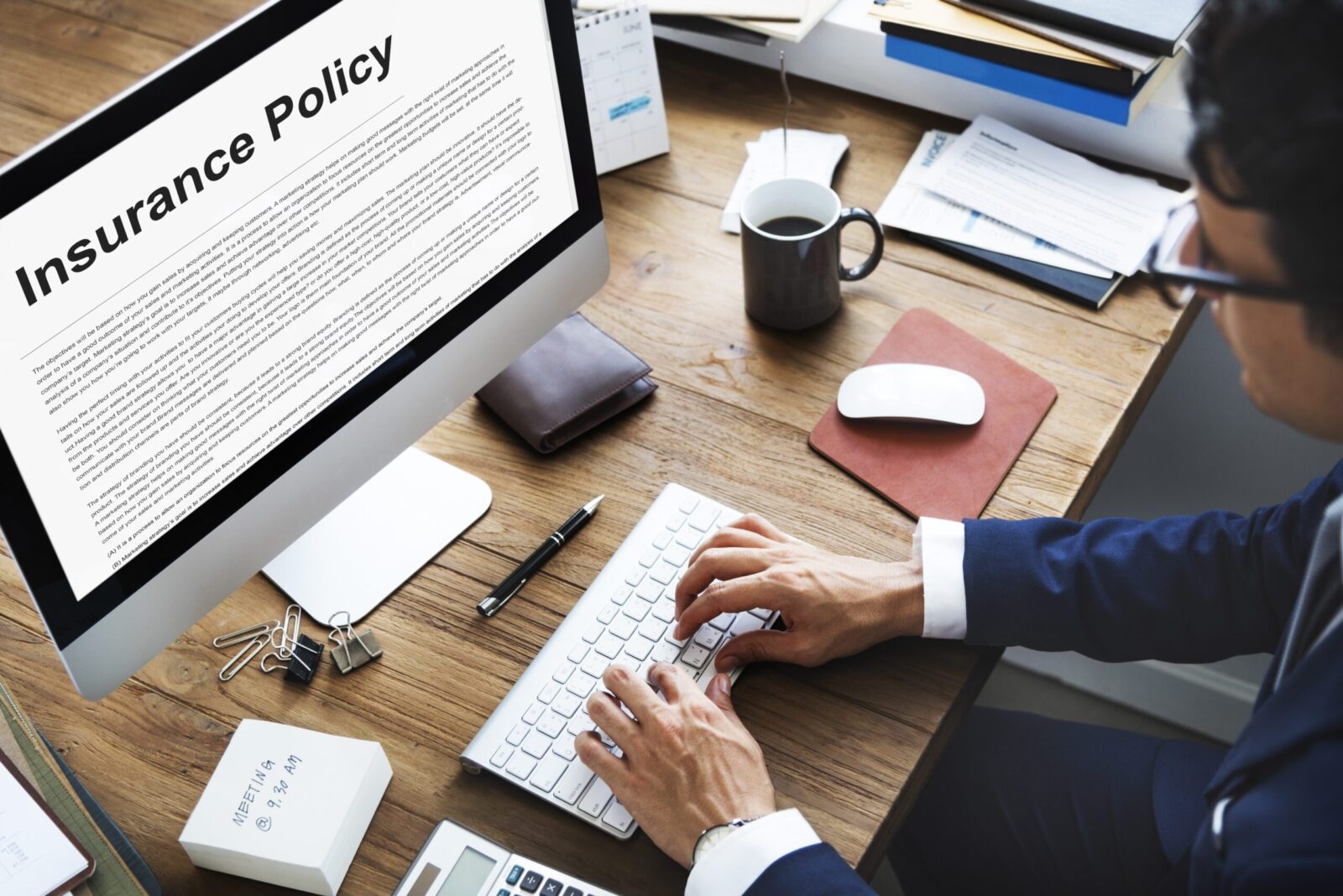 A man in front of his computer while looking into Insurance Policy