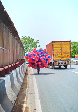 A balloon vendor driving a bicycle beside a truck